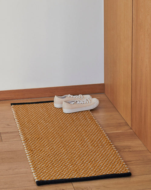 Long ochre HAY door mat with textured rug design, ideal for entryways and outdoor use.
